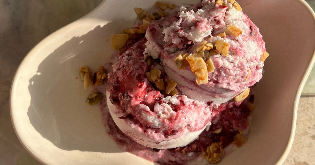 Blackberry and coconut ice cream in a bowl, swirled with berry compote and topped with grain-free granola