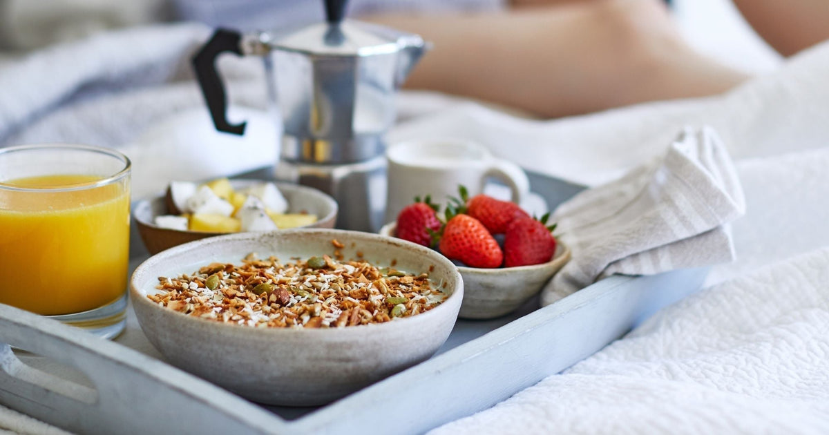 Tray with Paleo cereal and a glass of orange, sat on a bedside