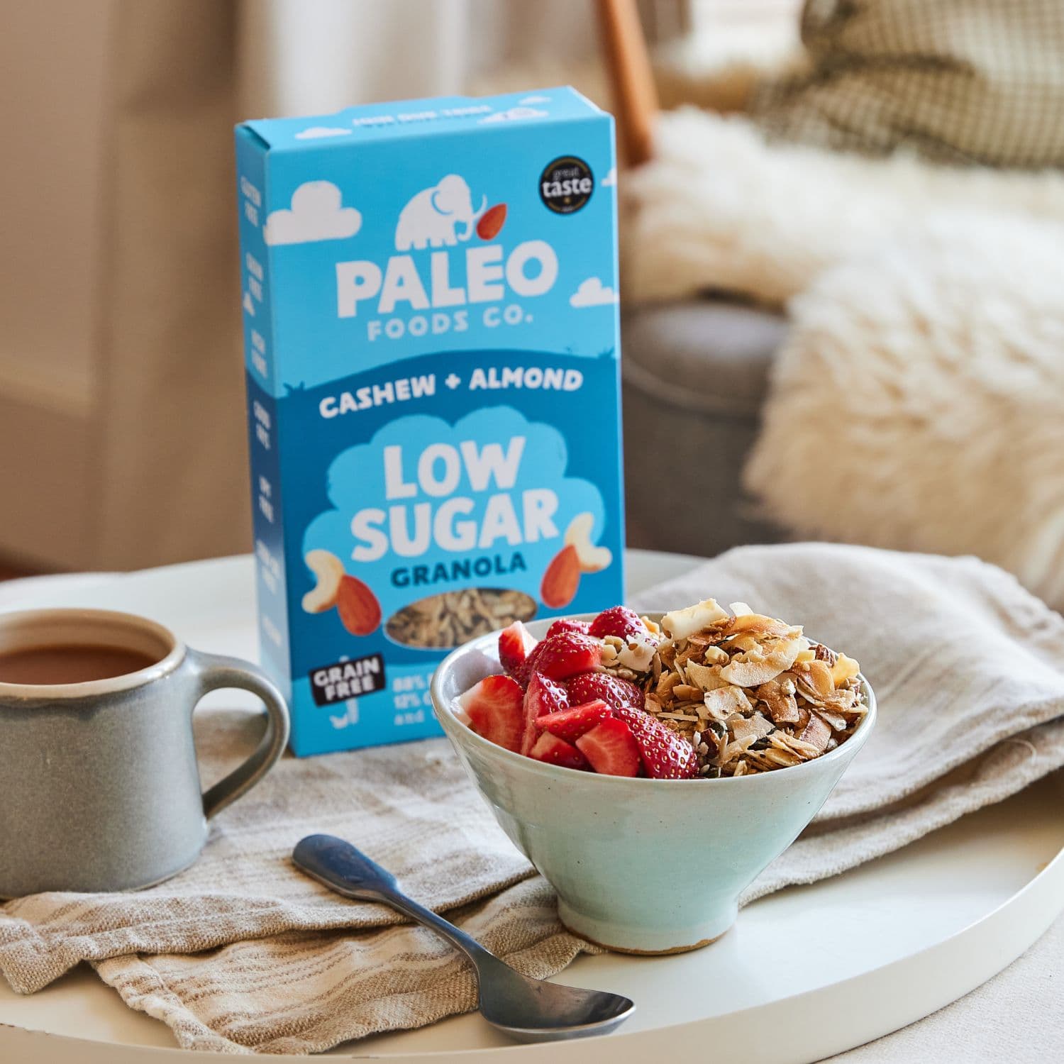 Bowl of cereal with Paleo Foods Co. granola and a cup of coffee on a table.
