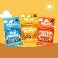 Three Paleo Foods Co. granola snack boxes are shown on a warm yellow-orange background with simple cloud and sun illustrations.