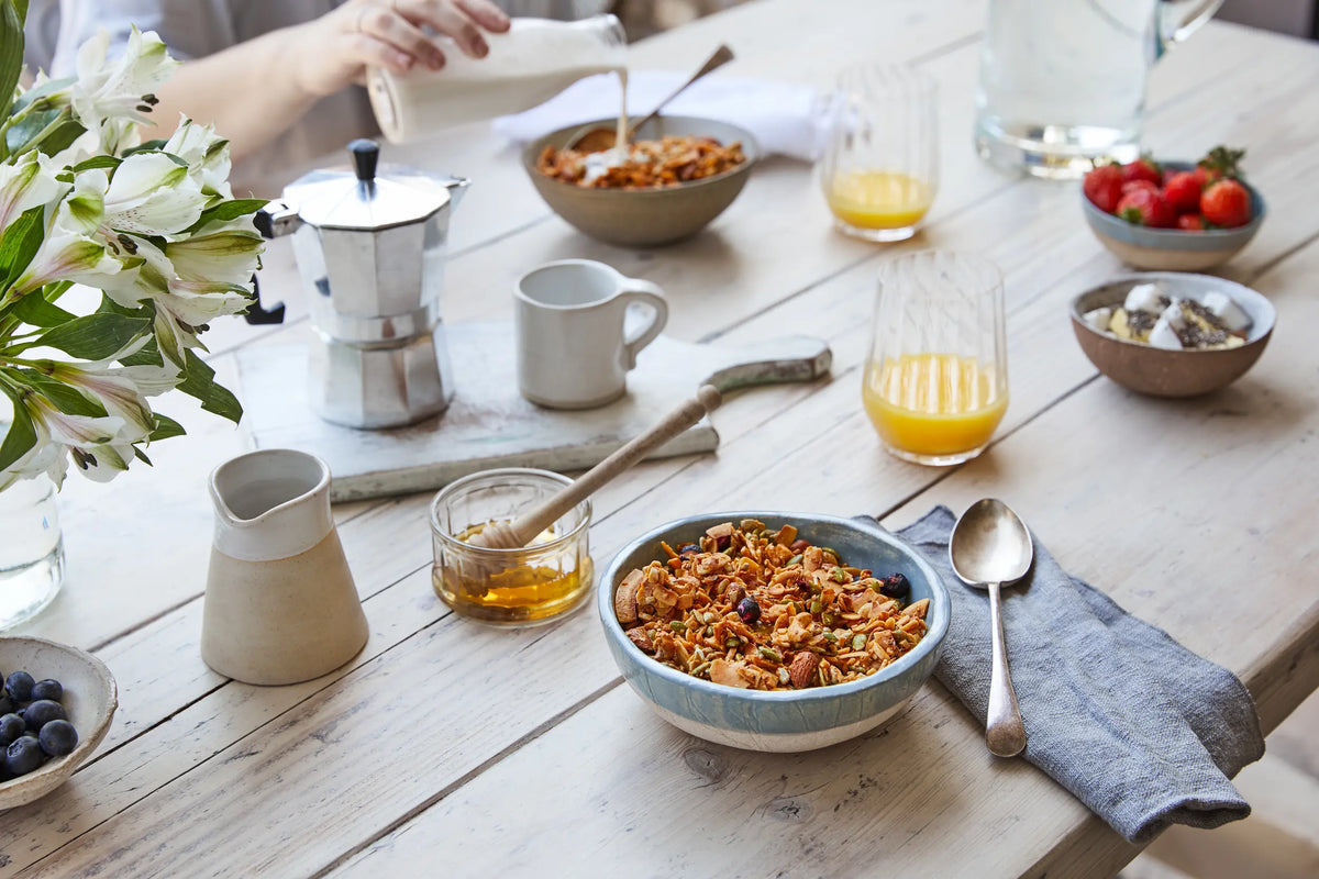 Breakfast table with a bowl of Paleo Foods Co. Original Nutty pecan and almond granola, berries and coffee